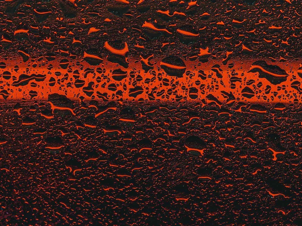 Raindrops on glass with red car light bokeh