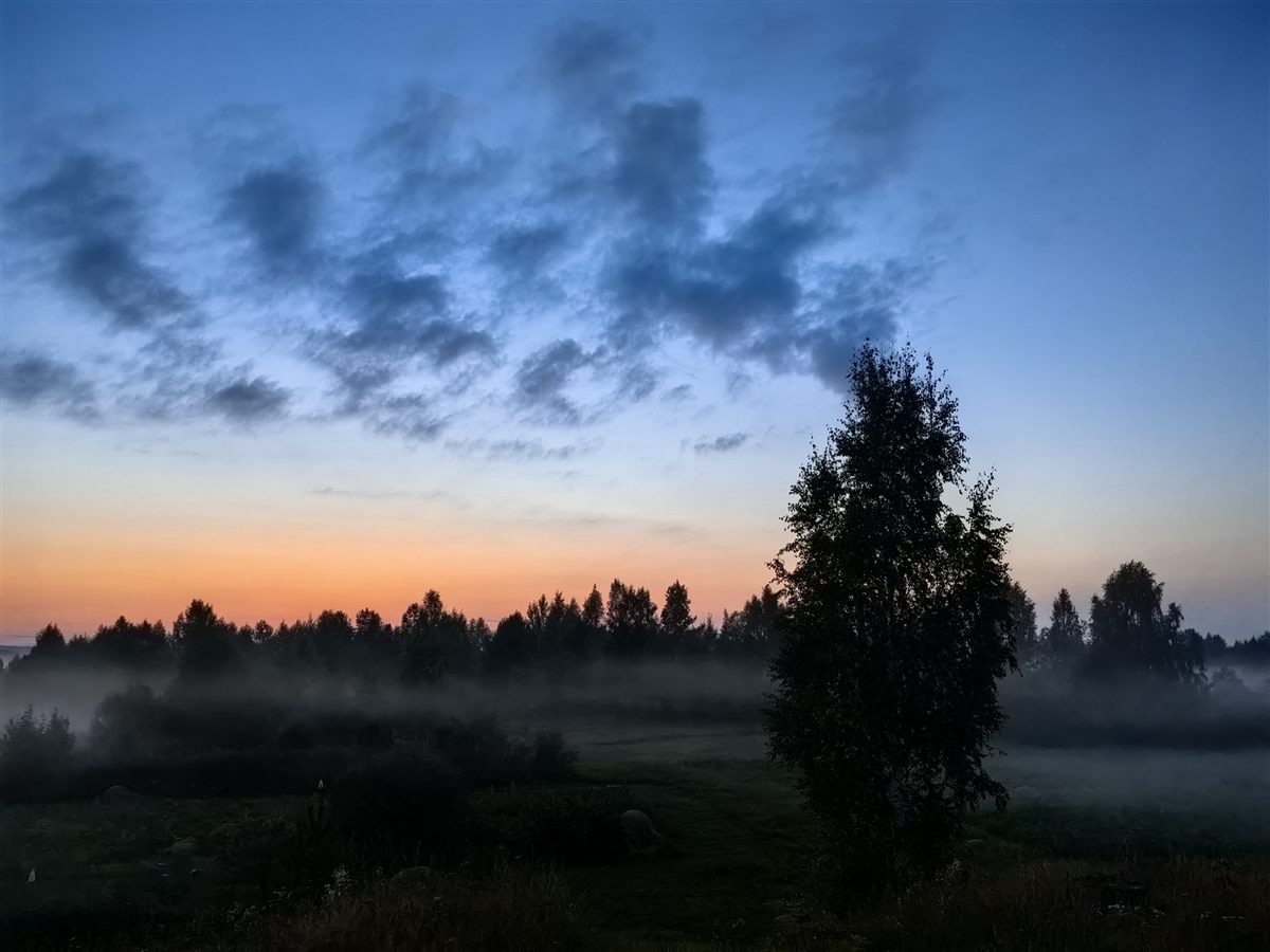 Sunset gradient from blue to orange with torn clouds and fog