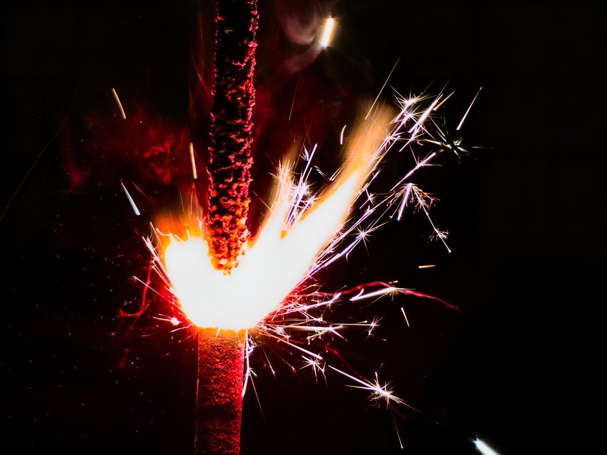 Bright red sparkler with flying sparks